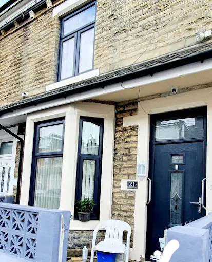 Modern dark grey double glazing bay windows and matching front composite door installed on a brick home terraced exterior.
